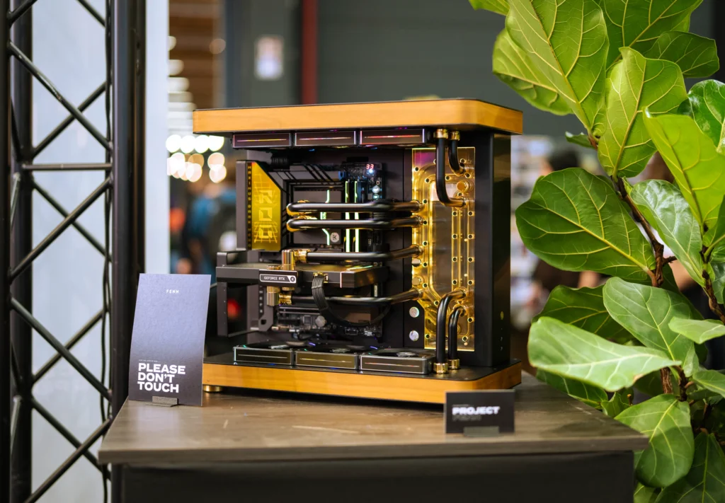 Custom gold-accented water-cooled PC powered by Seasonic, displayed at FENN’s FACTS 2025 booth.