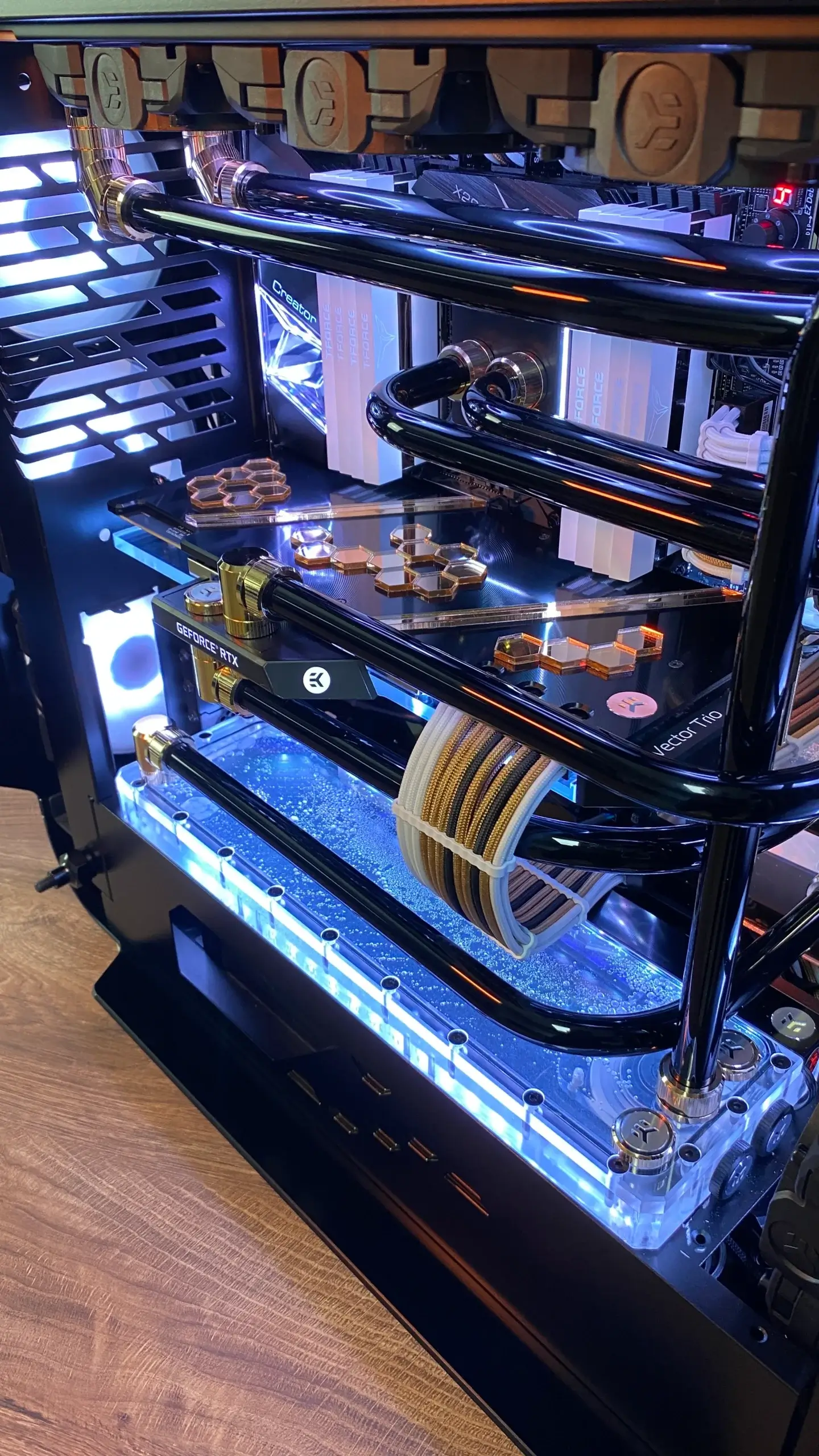 Front angle of the Black Gold custom PC showing chrome hard-line tubing, gold fittings, and illuminated reservoir.